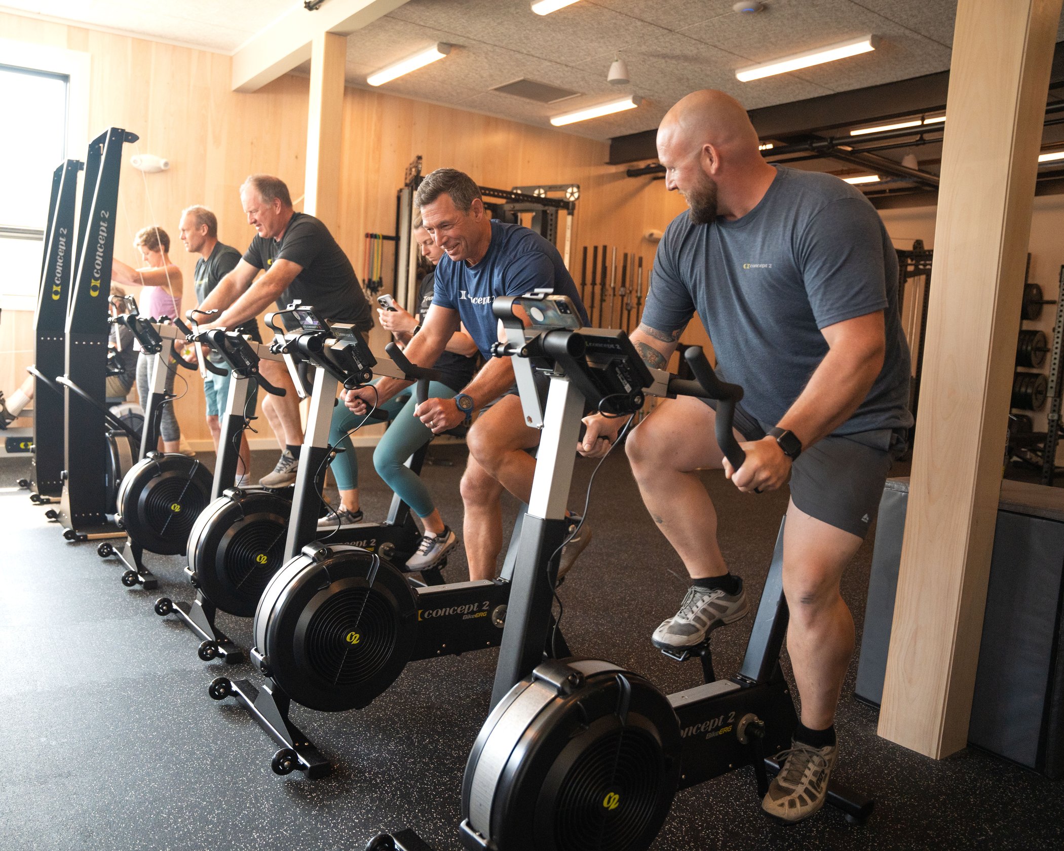 A group of people working out on SkiErgs and BikeErgs in a gym
