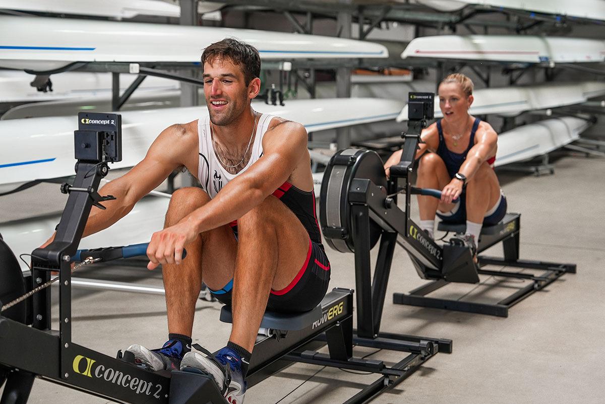 man and woman using Concept2 rowing machines with slides